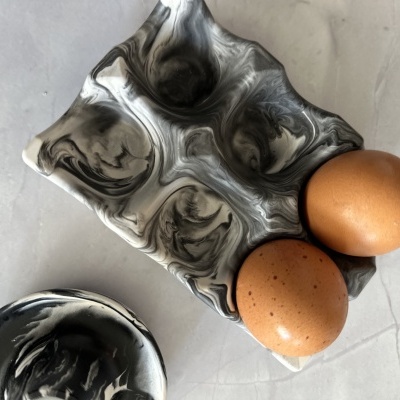 Tabuleiro marmoreado para ovos com dois ovos castanhos em superfície branca