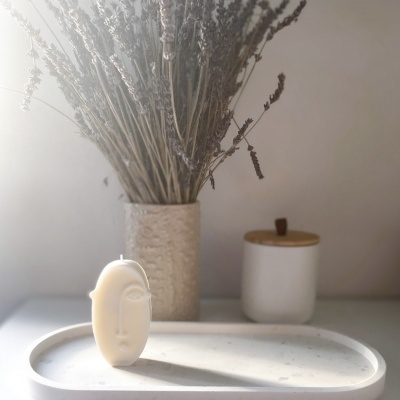 Vela em forma de rosto, frasco com flores secas e jarro com tampa de madeira