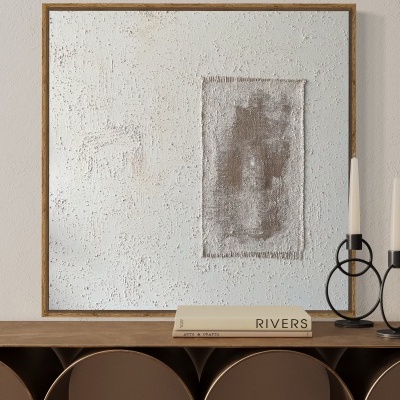 Conjunto de decoração interior com mesa de madeira escura, quadro abstrato, dois castiçais de ferro e livro branco