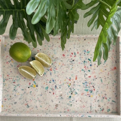 Tabuleiro retangular com padrão colorido tipo mármore, limas cortadas e folhas verdes