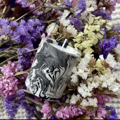 Vela marmoreada preta e branca rodeada de flores secas coloridas