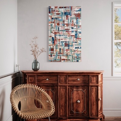 Móvel de madeira escura com cadeira de vime e quadro abstrato na parede