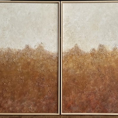 Dois quadros abstratos com tons castanhos e bege em molduras douradas sobre chão claro