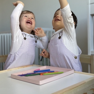 Duas crianças a brincar em mesa com lápis de cor e decoração interior