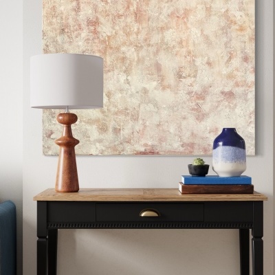 Consola preta com tampo de madeira com candeeiro, jarra, livros e planta, quadro abstrato na parede