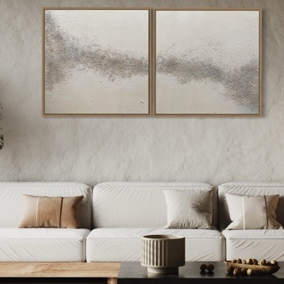 Sofá branco com almofadas bege e castanho, mesa de centro escura, decoração minimalista e pinturas abstratas neutras