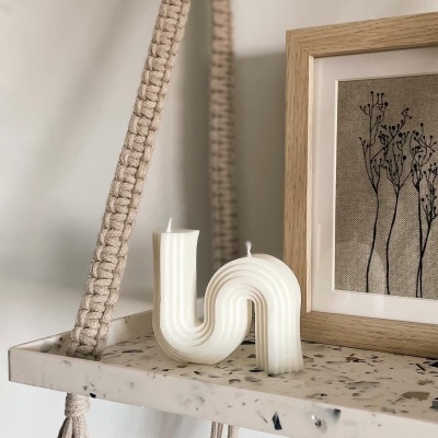 Vela branca em forma de arco na prateleira com moldura e ilustração de plantas