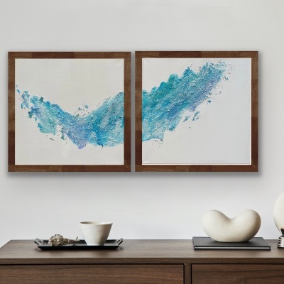 Móvel de madeira com quadros azuis abstratos e cerâmicas decorativas brancas em parede branca.