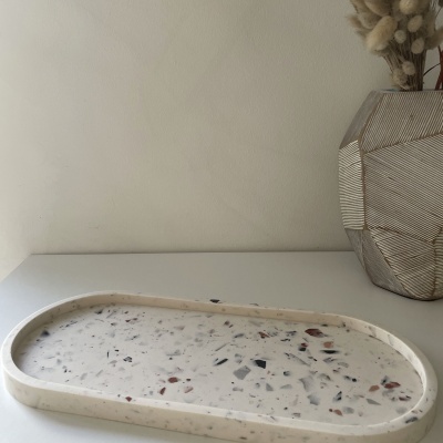 Tabuleiro oval de mármore decorativo com vaso cinzento e flores secas ao lado