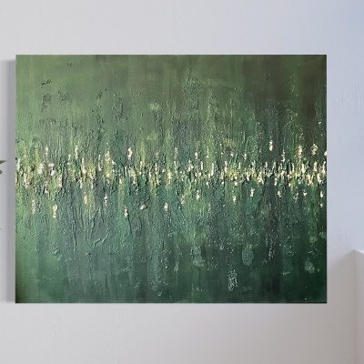 Tela de pintura abstrata verde com detalhes dourados numa parede branca, planta e janela ao lado