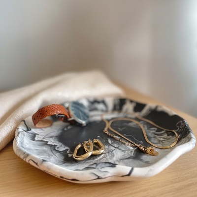 Prato decorativo marmoreado com acessórios dourados e pulseira de couro castanho