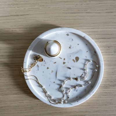 Prato redondo branco com padrão marmoreado a bege e castanho claro com anel dourado e colar de pérolas