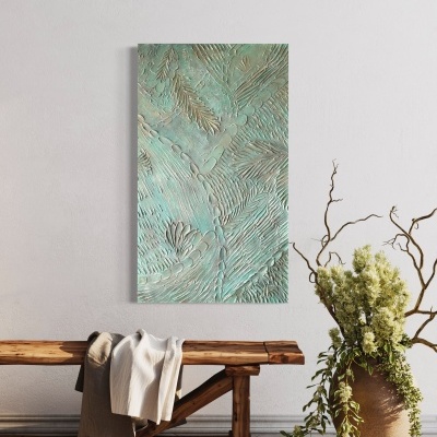 Quadro decorativo com relevo verde-azulado na parede, banco de madeira com tecidos e vaso com plantas