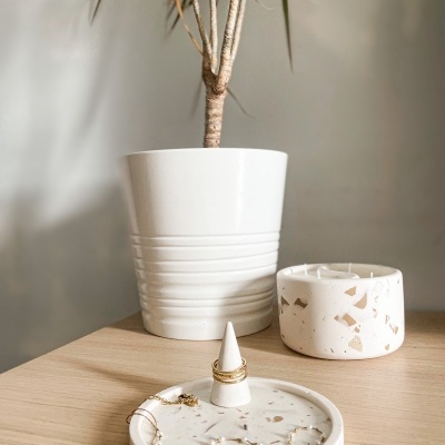 Vaso branco com planta, vela decorativa branca com padrão mármore e prato branco com textura mármore castanho claro com anel