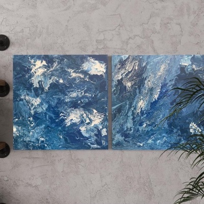 Dois quadros abstratos azuis pendurados numa parede cinzenta com estante e planta ao lado