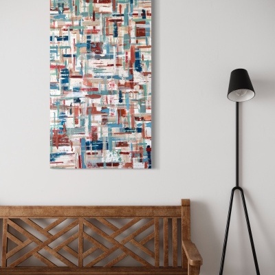 Quadro abstrato colorido numa parede, sobre banco de madeira e ao lado de candeeiro de pé.