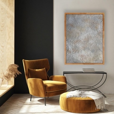 Poltrona e pufe mostarda em veludo com mesa de apoio e quadro abstrato numa sala