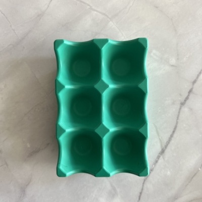 Forma de silicone verde para gelo ou ovos com seis cavidades sobre bancada marmore.