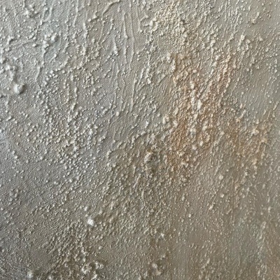 Parede branca e bege com textura áspera e relevos irregulares