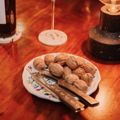 Prato com nozes e quebra-nozes sobre mesa de madeira com lâmpada e copo