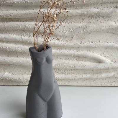 Vaso cinzento em forma de torso feminino com flores secas