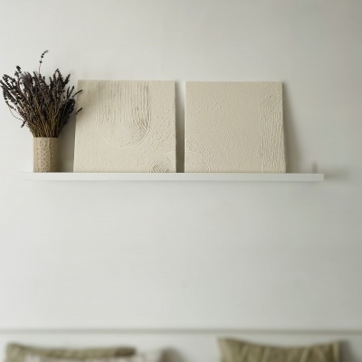 Prateleira branca com decoração minimalista, incluindo jarra com ramos secos e duas placas decorativas em relevo