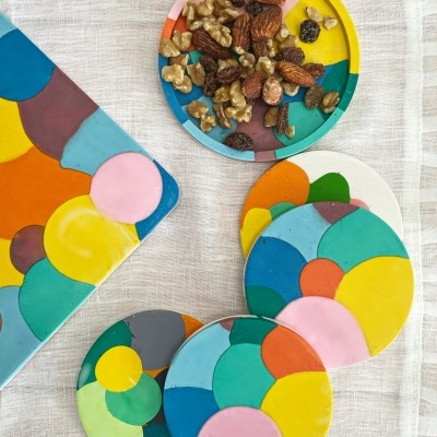 Bases para copos e prato pequeno coloridos com frutos secos em tecido branco