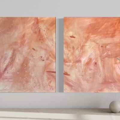 Dois quadros abstratos em tons quentes pendurados numa parede clara com adornos cerâmicos.