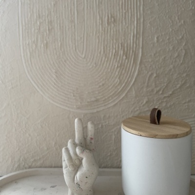 Vela em forma de mão e recipiente branco com tampa de madeira