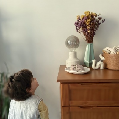 Cómoda de madeira com decoração incluindo vaso, flores secas, lâmpada decorativa, prato com objeto e vela branca