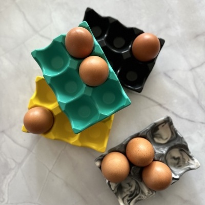 Caixas coloridas de ovos com ovos castanhos sobre superfície cinza clara