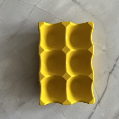 Forma amarela de silicone para ovos com seis cavidades sobre superfície de mármore