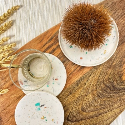 Bases redondas decorativas em branco com padrões coloridos, copo de vidro e ouriço castanho sobre tábua de madeira