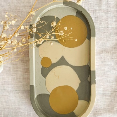 Tabuleiro oval colorido com padrão abstrato e ramos secos ao lado