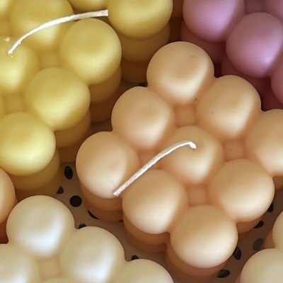 Velas em formato de bolhas coloridas em amarelo, rosa, bege e branco.
