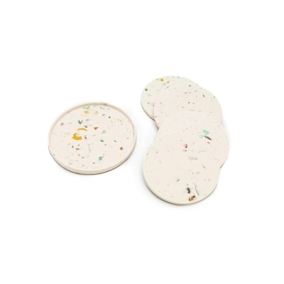 Conjunto de cinco bases para copos redondas em terrazzo branco com fragmentos coloridos.