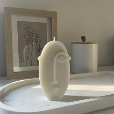 Castiçal branco abstrato em forma de rosto sobre bandeja branca marmoreada