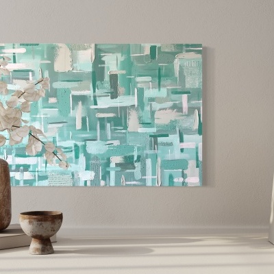 Tela abstrata verde e branco numa parede com vaso castanho, flores secas, tigela e livros brancos numa mesa.