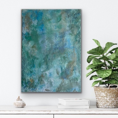 Quadro abstrato azul e verde com textura pendurado na parede ao lado de planta em vaso e objeto decorativo