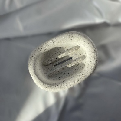 Pedra de sapo esculpida cinzenta com cavidade central, fundo branco desfocado