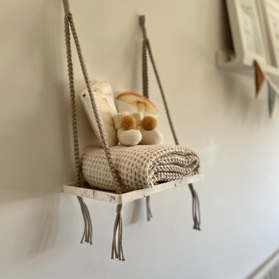 Prateleira suspensa com cobertor de malha bege e objectos de decoração em parede clara