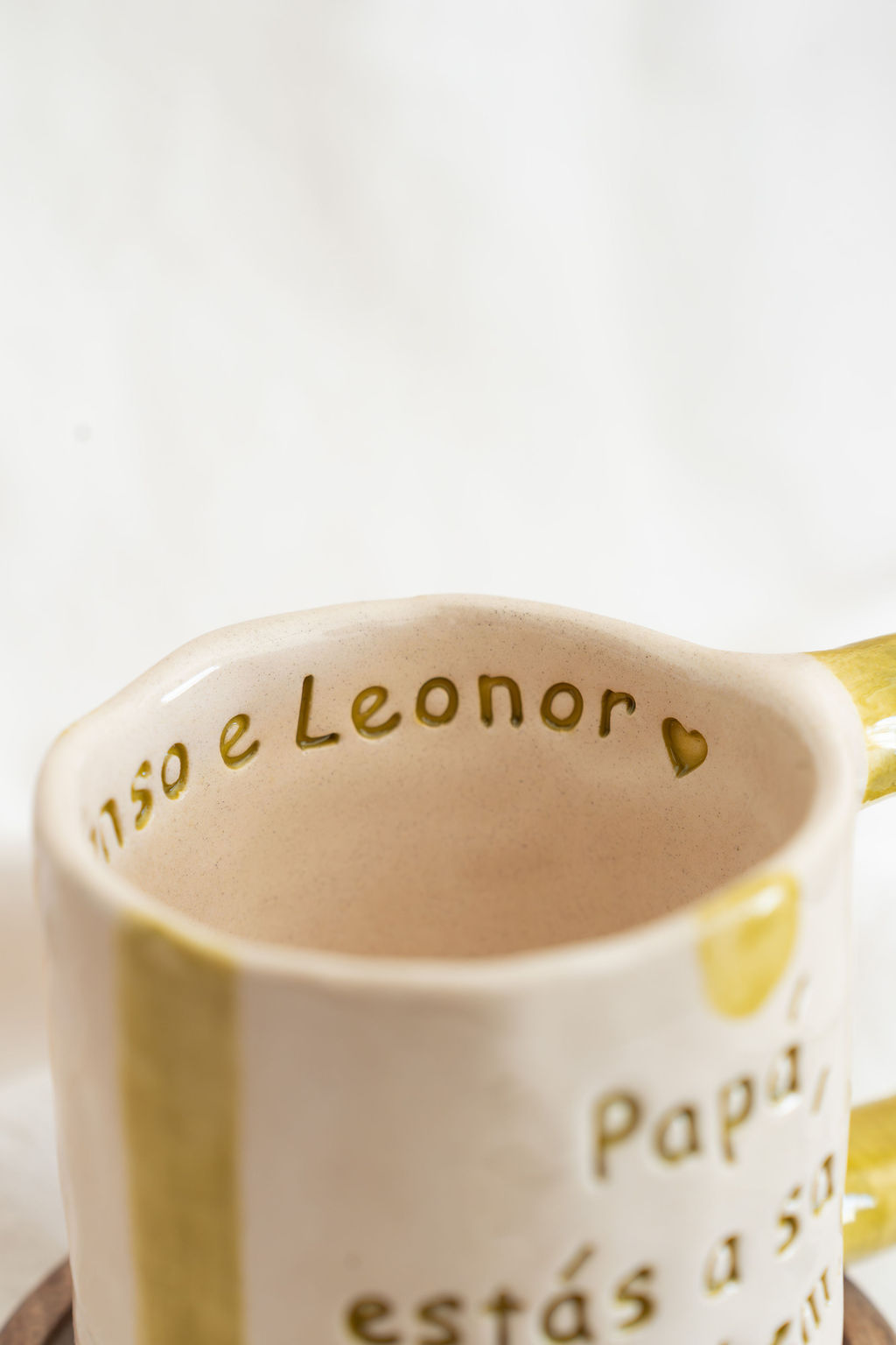 Caneca cerâmica creme com texto em relevo e risca amarela