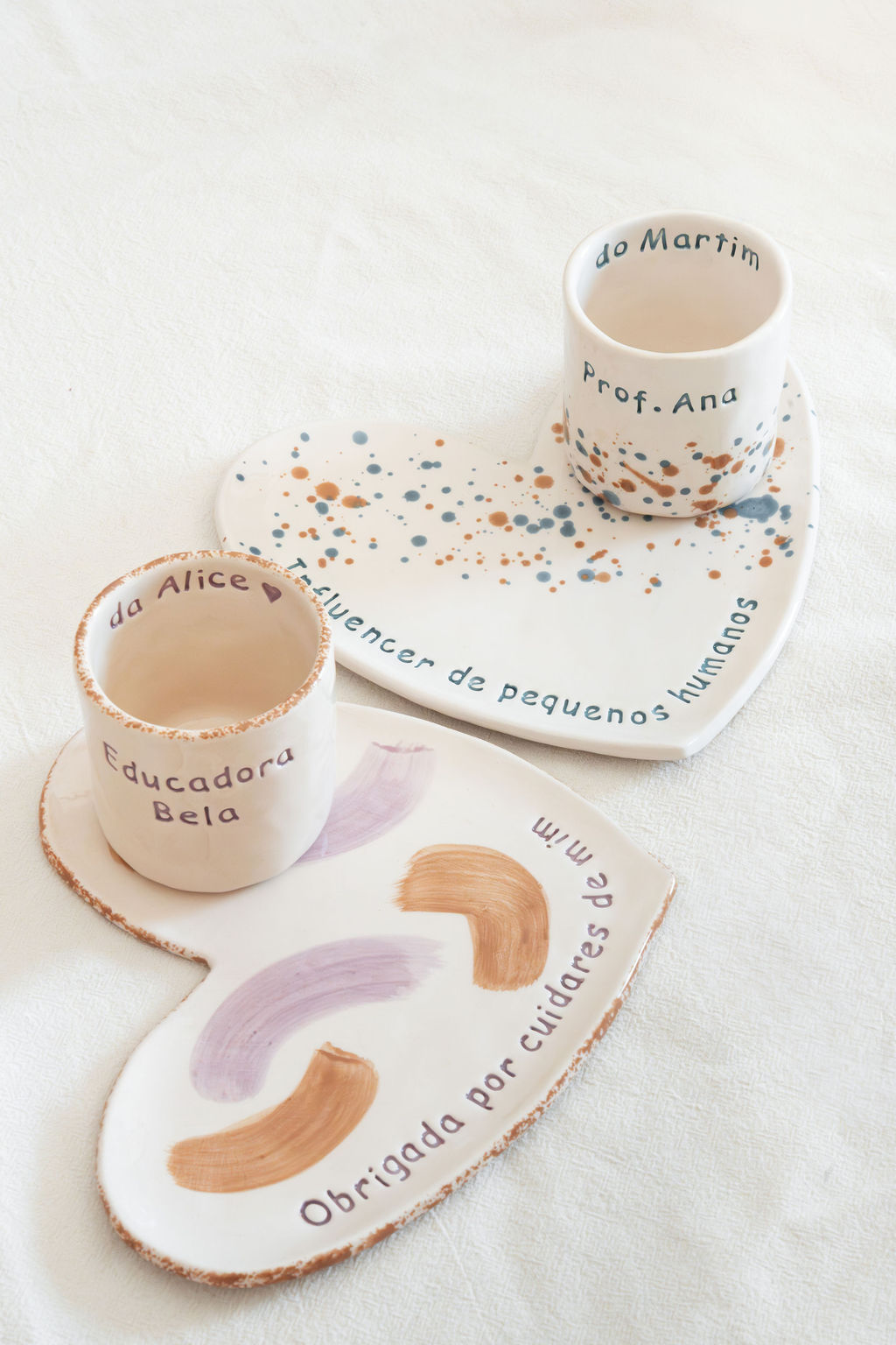 Conjunto de cerâmica branca com copos e pratos em forma de coração com decoração e texto