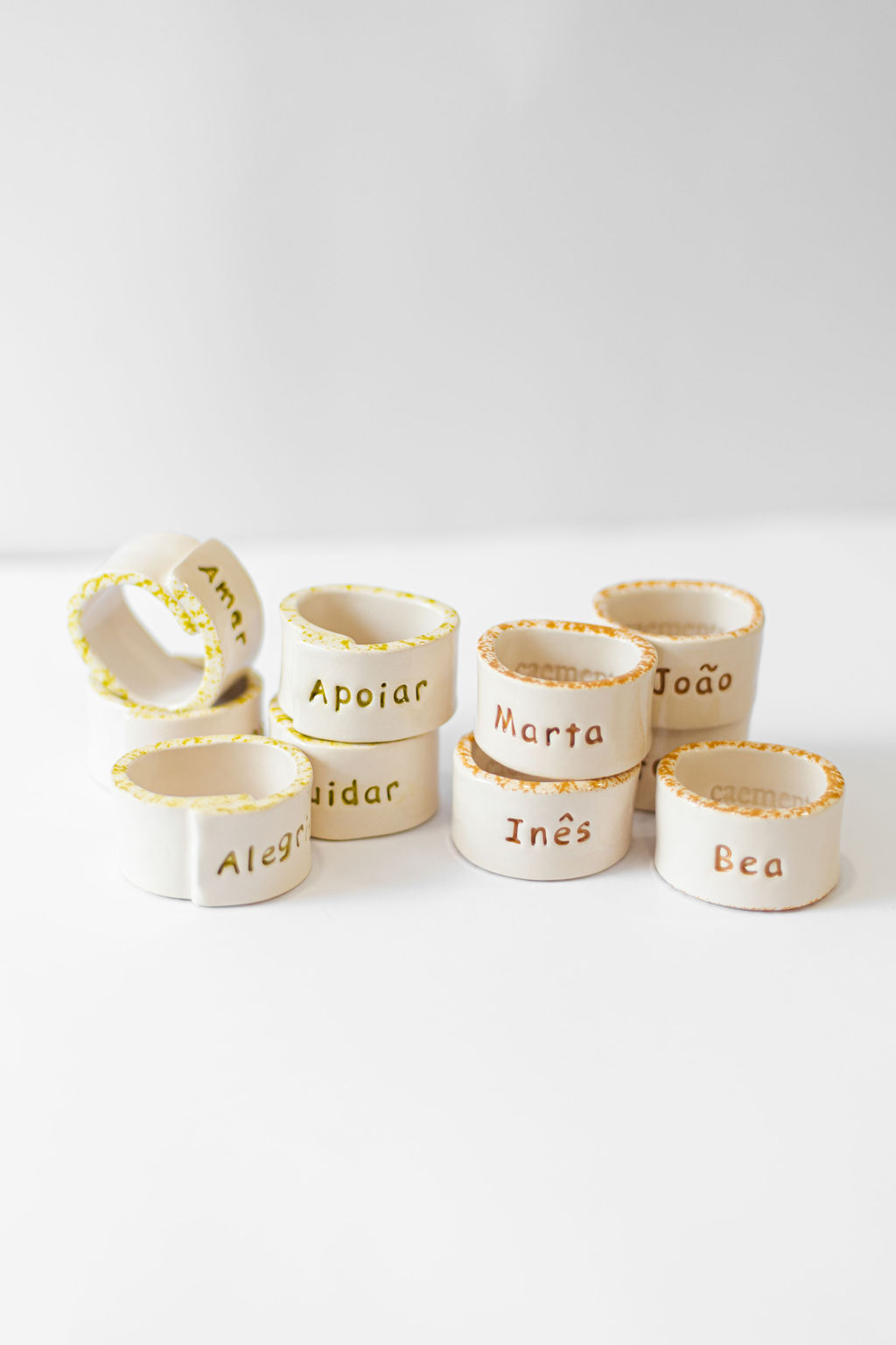 Anéis de cerâmica branca com nomes e palavras gravadas em português