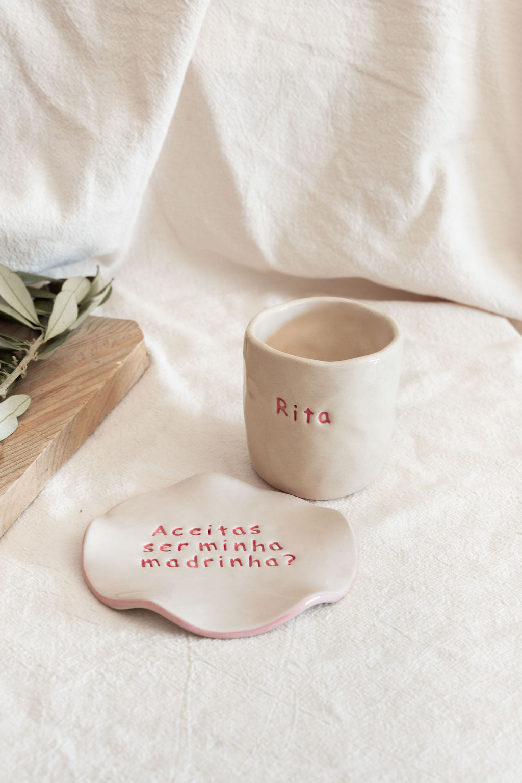 Chávena branca com o nome Rita e pires com texto Aceitas ser minha madrinha em cerâmica branca e vermelha