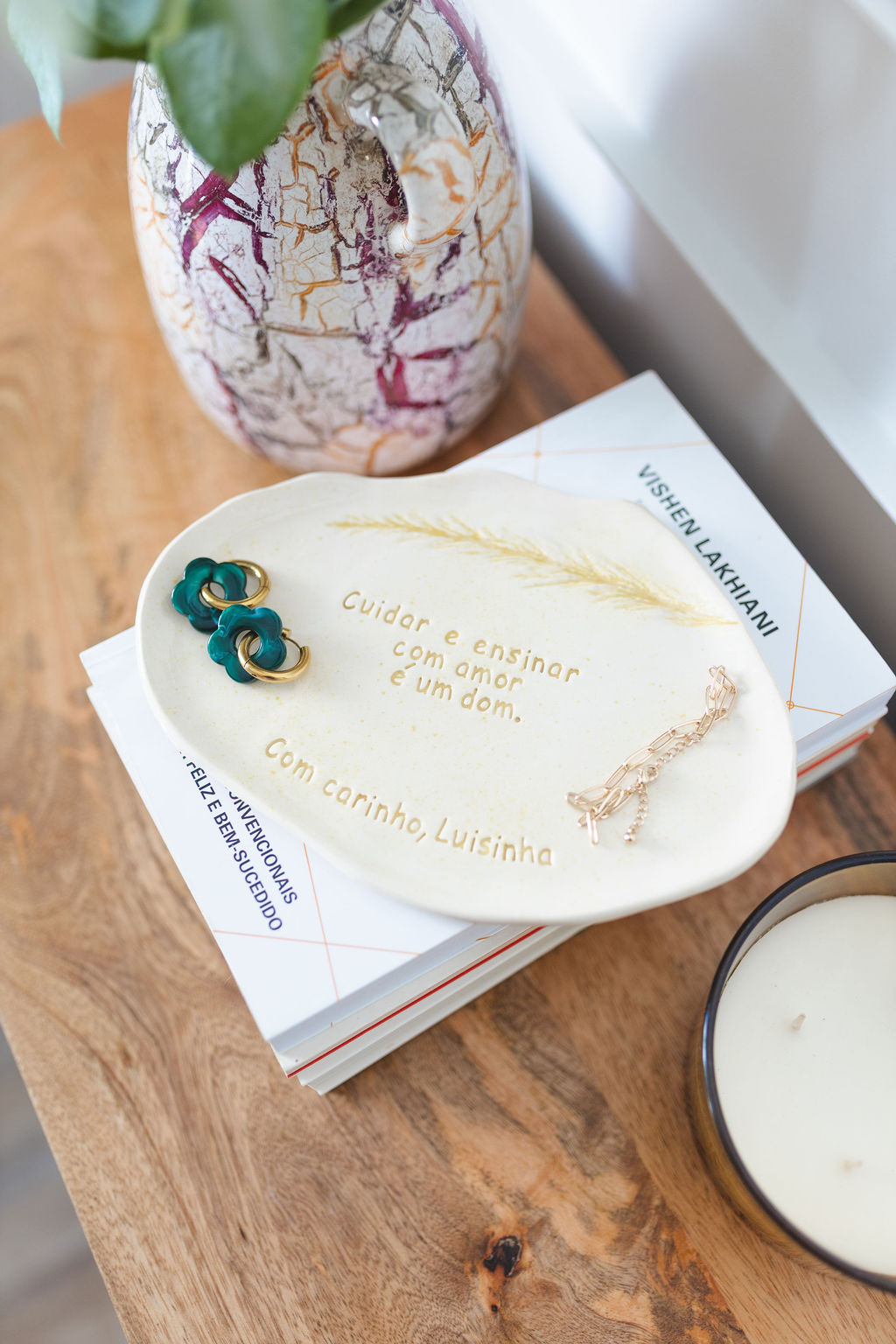 Prato decorativo branco com mensagem em português e jarra cerâmica colorida em fundo