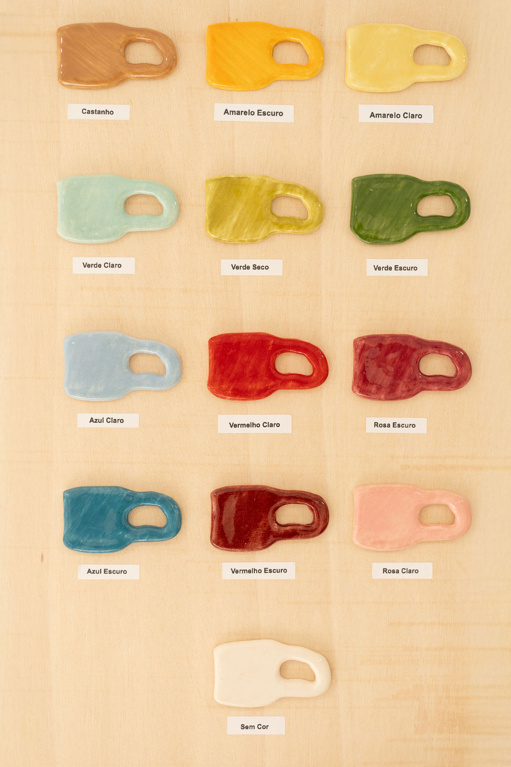 Amostras coloridas de revestimentos cerâmicos em forma de caneca, com etiquetas de cores em português.