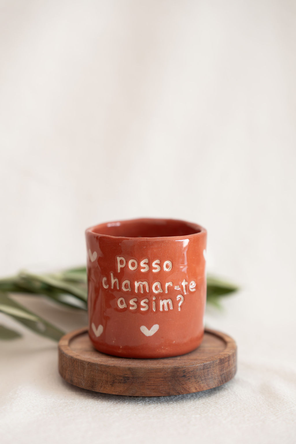 Caneca vermelha com texto branco sobre suporte de madeira