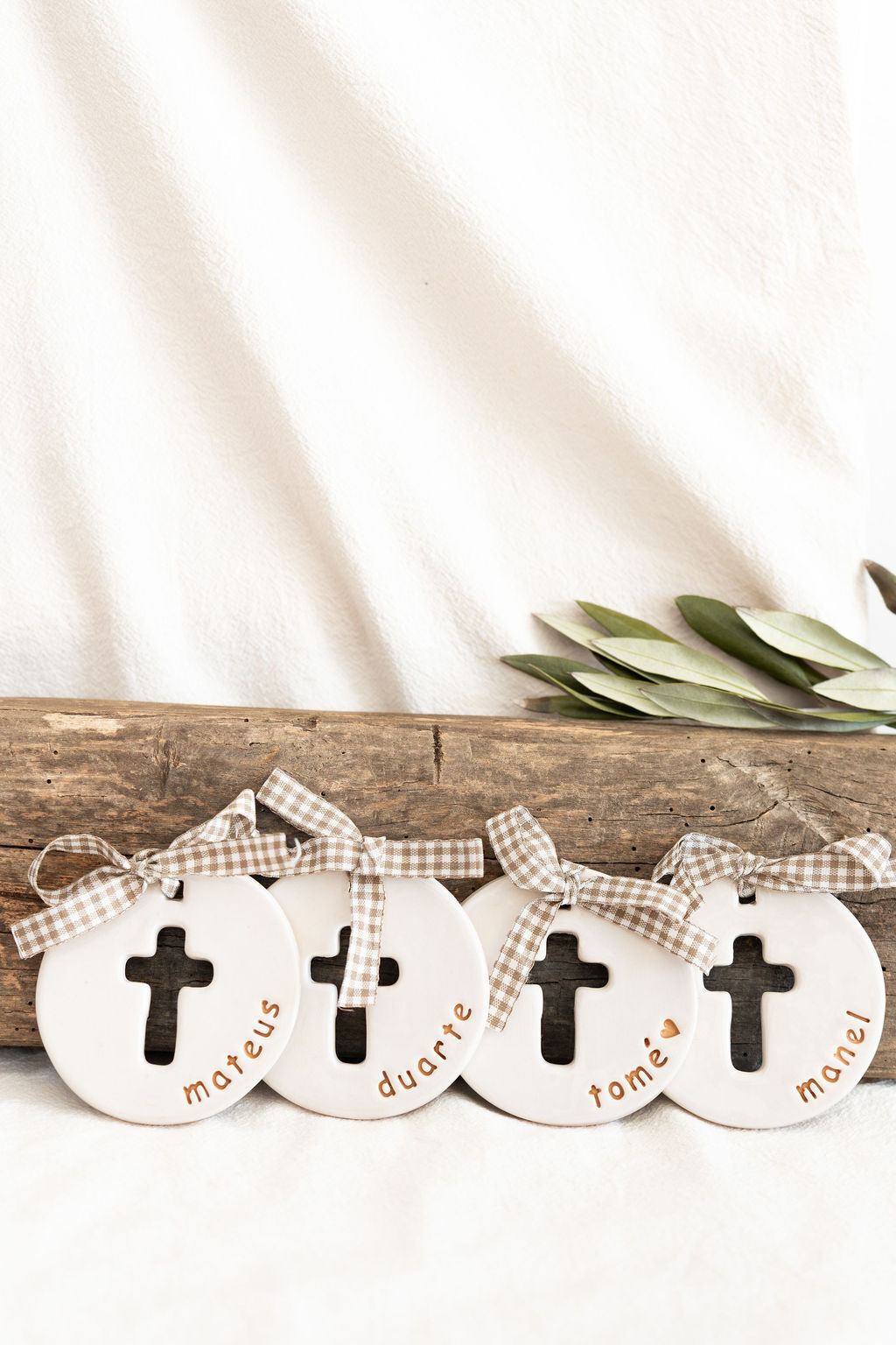 Ornamentos redondos brancos com cruz e nomes à mão colocados sobre madeira