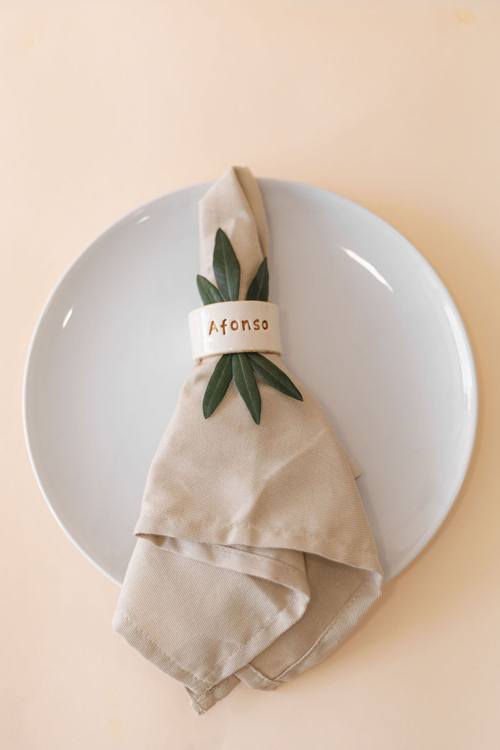 Guardanapo bege com anel personalizado Afonso em prato branco